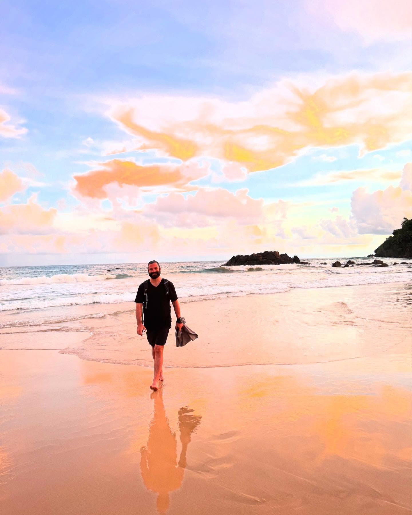 Matt walking a tropical beach at sunset with snorkel gear