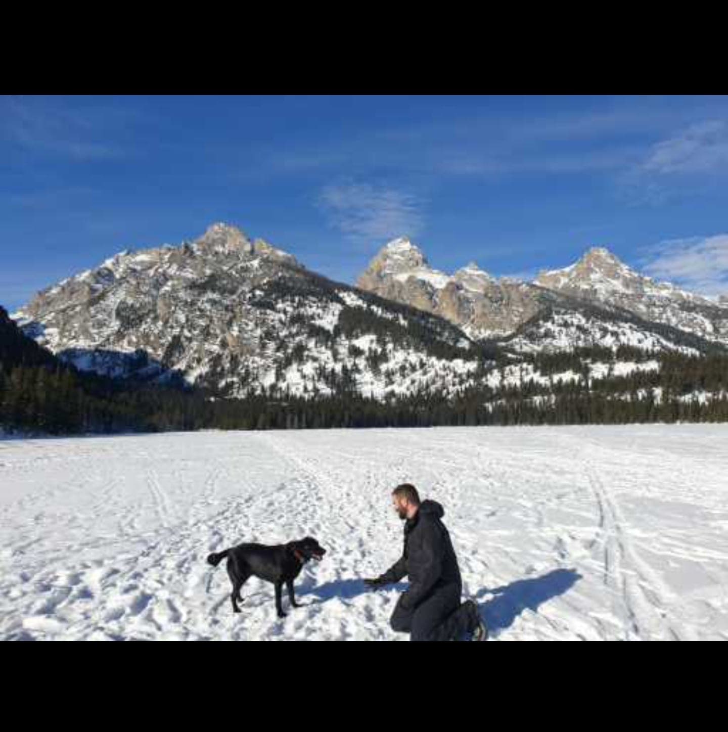 Matt and his black dog in front of the Tetons in winter