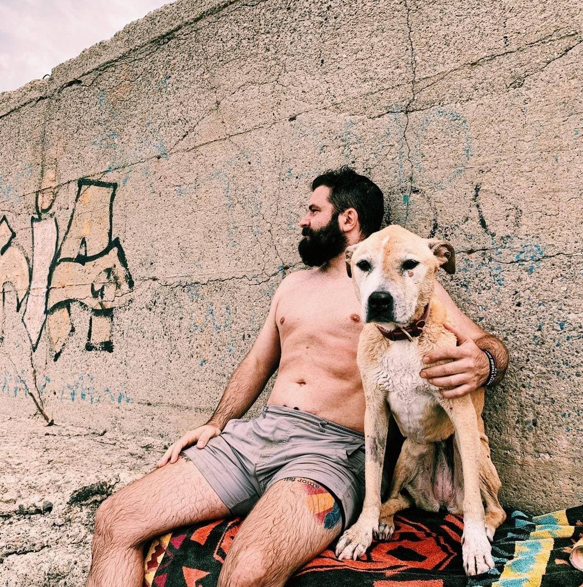 Matt resting against a graffiti wall with his rescue dog